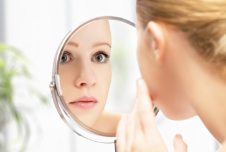 a lady looking in the mirror at her acne scarring